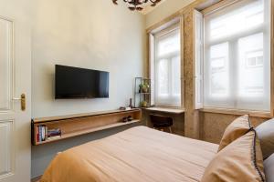 a bedroom with a bed and a flat screen tv at Sé Apartamentos - Miau Apartment in Braga