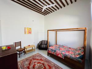 een slaapkamer met een bed, een stoel en een tafel bij Happy House Nungwi in Nungwi
