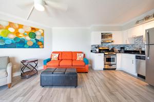a living room with an orange couch and a kitchen at Emerald on the Water - Formerly Belleair Beach Club in Clearwater Beach