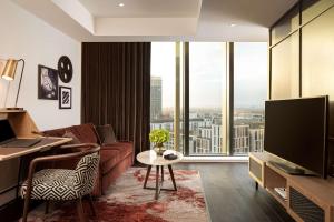 uma sala de estar com um sofá e uma grande janela em The Gantry London, Curio Collection By Hilton em Londres