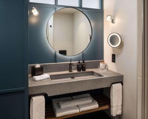 uma casa de banho com um lavatório e um espelho em The Gantry London, Curio Collection By Hilton em Londres