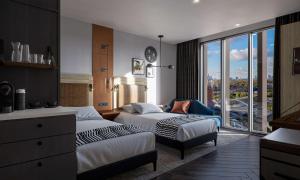 a hotel room with two beds and a large window at The Gantry London, Curio Collection By Hilton in London