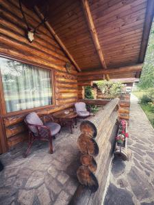 a porch of a log cabin with chairs and tables at Sunset By The Farm in Piatra Neamţ