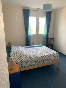 a bedroom with a bed with a blue comforter and a window at Villa feng shui in Fargues-de-Langon