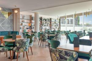 a restaurant with green chairs and tables and windows at Hilton London Angel Islington in London