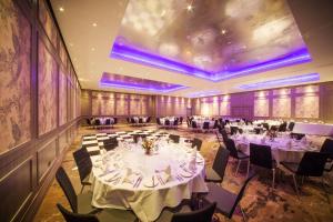 キングストン・アポン・テムズにあるダブルツリー バイ ヒルトン ロンドン キングストン アポン テムズの白いテーブルと椅子、紫色の照明が備わる宴会場