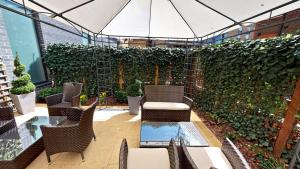 un patio con sillas, mesas y una pared verde en DoubleTree by Hilton London Angel Kings Cross en Londres