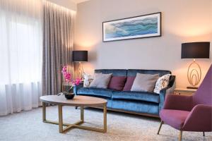 a living room with a blue couch and a table at DoubleTree by Hilton London Angel Kings Cross in London