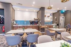 a restaurant with tables and chairs and a counter at DoubleTree by Hilton London Angel Kings Cross in London