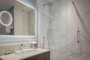 a bathroom with a shower and a sink and a mirror at DoubleTree by Hilton London Angel Kings Cross in London