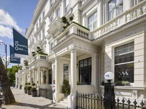 ein weißes Gebäude mit einem Ball auf einem Zaun in der Unterkunft 100 Queen’s Gate Hotel London, Curio Collection by Hilton in London