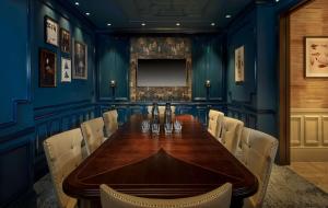 100 Queen’s Gate Hotel London, Curio Collection by Hilton في لندن: غرفة طعام مع طاولة خشبية وجدران زرقاء