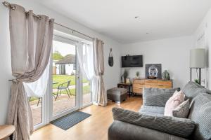 a living room with a couch and a sliding glass door at Lytton Tree Lodge- 7 Self-Contained Lodges in Reydon