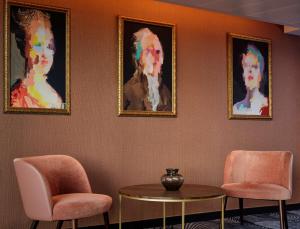 a room with two chairs and a table and paintings at The Westminster London, Curio Collection by Hilton in London