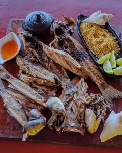 a bunch of fish on a cutting board with dipping sauce at Rancho Dias in Atins