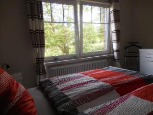 a bedroom with a bed with a quilt and a window at Salthuus Ostfriesland in Friedeburg