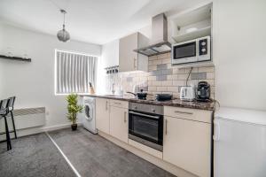 a white kitchen with a microwave and a dishwasher at Leicester City Center The Boat House Building in Leicester