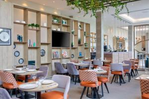 a restaurant with tables and chairs and a flat screen tv at Hilton Garden Inn Stoke On Trent in Stoke on Trent