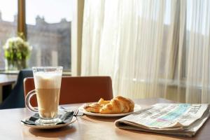 eine Tasse Kaffee und Croissants auf einem Tisch mit einer Zeitung in der Unterkunft Hampton by Hilton Newcastle in Newcastle upon Tyne