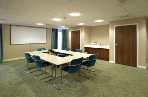 a conference room with a table and chairs and a whiteboard at Hampton by Hilton Corby in Corby