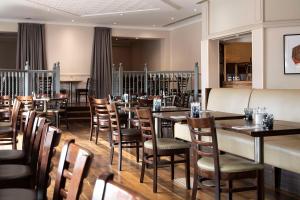 a dining room with wooden tables and chairs at DoubleTree by Hilton Swindon Hotel in Swindon