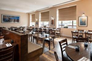 a restaurant with wooden tables and chairs and windows at DoubleTree by Hilton Swindon Hotel in Swindon