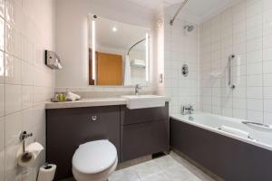 a bathroom with a toilet and a sink and a tub at DoubleTree by Hilton Swindon Hotel in Swindon