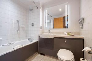 a bathroom with a tub and a sink and a toilet at DoubleTree by Hilton Swindon Hotel in Swindon