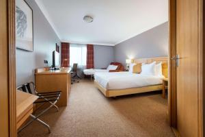 a hotel room with two beds and a desk at DoubleTree by Hilton Swindon Hotel in Swindon