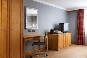 a room with a desk and a mirror and a chair at DoubleTree by Hilton Swindon Hotel in Swindon