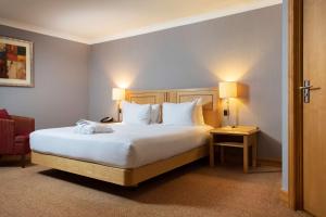 a bedroom with a large bed with white sheets and pillows at DoubleTree by Hilton Swindon Hotel in Swindon
