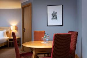 a room with a table and chairs and a bed at DoubleTree by Hilton Swindon Hotel in Swindon