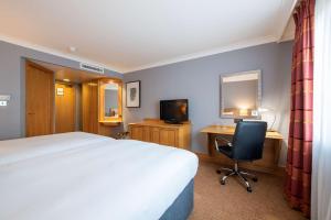 a bedroom with a bed and a desk and a television at DoubleTree by Hilton Swindon Hotel in Swindon