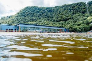 un edificio frente a una montaña con una masa de agua en Hilton Garden Inn Snowdonia en Conwy