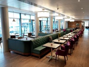 a restaurant with long tables and chairs and windows at Hilton Garden Inn Birmingham Brindley Place in Birmingham
