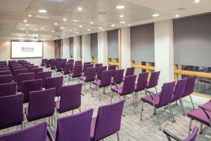 una sala de conferencias con sillas púrpuras y una pantalla en Hilton Garden Inn Birmingham Brindley Place en Birmingham