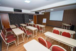 uma sala de aula com mesas e cadeiras e uma tela de projeção em H+ Hotel em Dourados