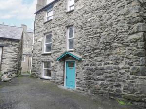 una vieja casa de piedra con una puerta azul en 5 Tai Isa, en Barmouth