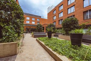 een binnenplaats met banken en planten voor een gebouw bij The Fellows House Cambridge, Curio Collection By Hilton in Cambridge