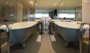 a bathroom with three sinks and two bath tubs at DoubleTree by Hilton Coventry Building Society Arena in Coventry