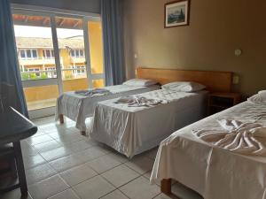 two beds in a hotel room with a window at Hotel Uirapuru in Goianesia do Para
