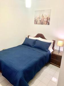 a bedroom with a blue bed and a nightstand with a lamp at Hab Nawi con Aire Acondicionado in Cali