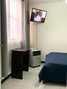 a bedroom with a bed and a tv on the wall at Hab Nawi con Aire Acondicionado in Cali