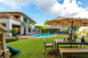 um quintal com uma mesa e um guarda-sol e uma piscina em Sunny Vacation Villa No 71 em San Rafael del Yuma