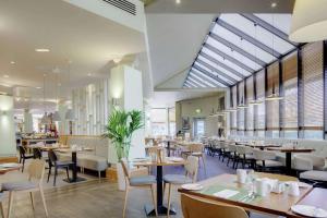 uma sala de jantar com mesas, cadeiras e janelas em DoubleTree by Hilton Manchester Airport em Hale