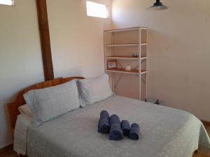Una cama con dos pares de zapatillas azules. en Hotel-Camping Takha Takha, en San Pedro de Atacama