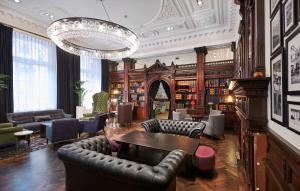 利物浦的住宿－利物浦希爾頓逸林酒店，一个带皮革家具和吊灯的图书馆