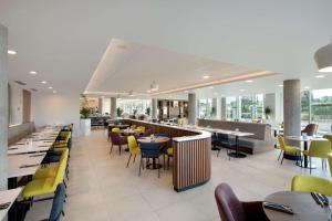 a restaurant with tables and chairs and a bar at Hampton By Hilton London Stansted Airport in Stansted Mountfitchet
