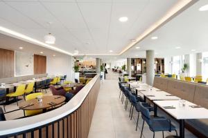 a dining room with tables and yellow chairs at Hampton By Hilton London Stansted Airport in Stansted Mountfitchet
