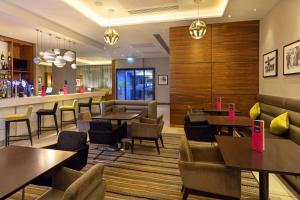 a restaurant with tables and chairs and a bar at Hampton by Hilton London Croydon in Croydon